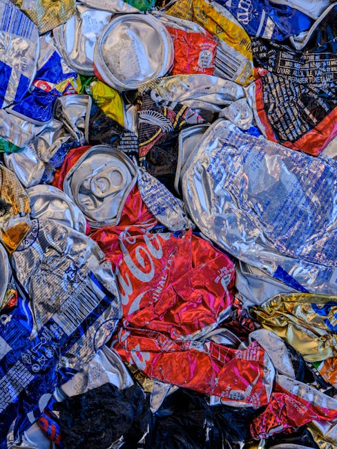 A tightly tied black plastic rubbish bag with a glossy surface, placed in front of a plain, light-colored wall. The bag appears full and slightly bulging, with some creases and folds visible on its surface. In the background, other black rubbish bags are stacked or leaning against each other, indicating a collection of waste awaiting disposal. The setting suggests an outdoor or indoor space designated for rubbish storage, such as a driveway, alleyway, or waste collection area. The lighting is neutral, casting soft shadows on the bags and highlighting the reflective quality of the plastic material. This scene aligns with waste management practices and could relate to private rubbish collection services provided by companies like Rubbish Removal Harringay, especially in contexts where independent or supplementary waste disposal is performed outside of local authority collection services.